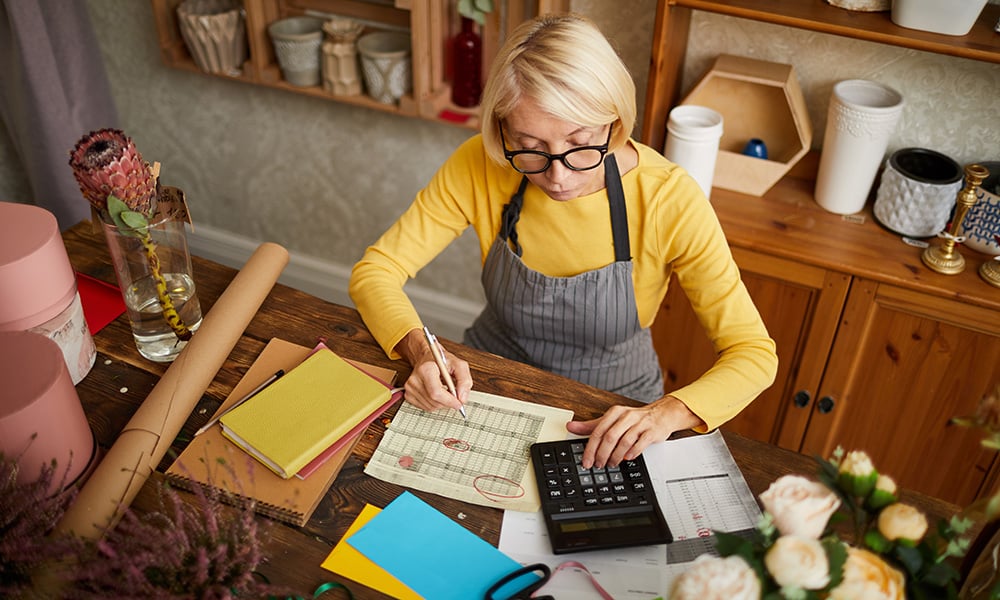 Florist managing finances and writing notes in flower shop